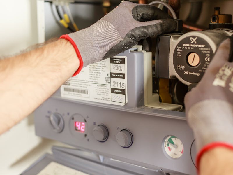 Heating engineer adjusting power flushing equipment on a central heating system