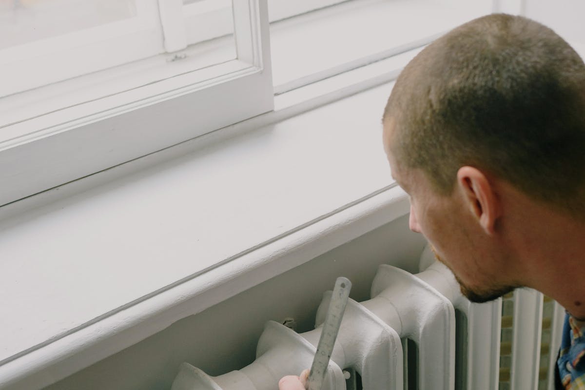 Engineer measuring and adjusting a new radiator installation in a Greater Manchester home